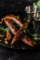 Grilled sausage on a dark plate with sauce