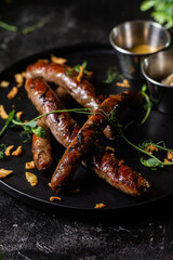 Grilled sausage on a dark plate with sauce