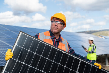 Young engineer inspect installation of solar panels installed check  with blueprint on the field, with recording inspection data on pc.