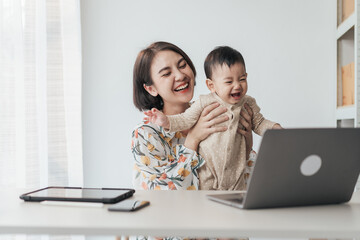 A boy Asian baby in mother's arms, and use computer laptop with video calls with father or...