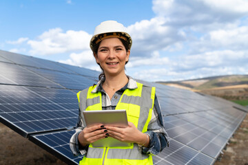 Portrait of female manager engineer in safety helmet checking with digital tablet an operation of solar panel system at solar station