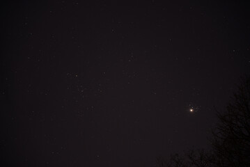 The planet Venus in the starry night sky in conjunction with the Pleiades Constellation. The group...