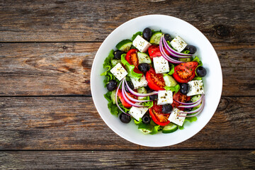 Greek style salad - fresh vegetables with feta cheese on wooden table
