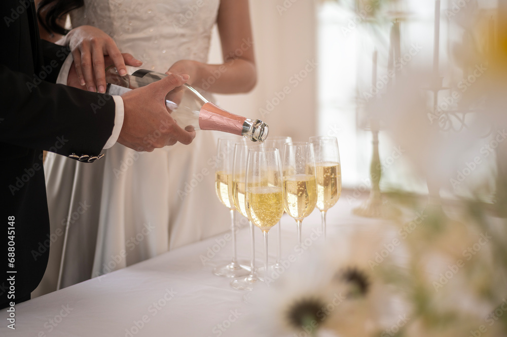 Wall mural Bride and groom holding glasses of champagne at the wedding ceremony