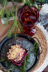 New Year's dinner with herring salad under a fur coat by candlelight and a glass of champagne. Festive table setting decorated with fluffy spruce and cones