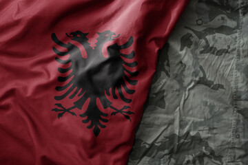 waving flag of albania on the old khaki texture background. military concept.
