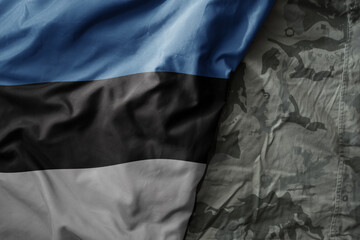 waving flag of estonia on the old khaki texture background. military concept.