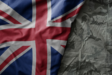 waving flag of great britain on the old khaki texture background. military concept.