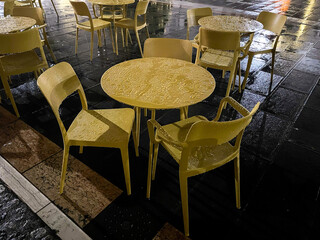 central square of San Vito al Tagliamento with rain during the Christmas period seen at night with wet colored tables