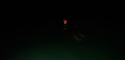 Authentic triathlete swimmer having a break during hard training on night