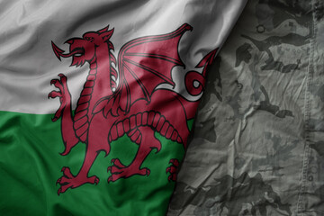 waving flag of wales on the old khaki texture background. military concept.
