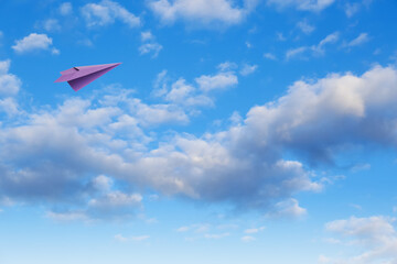 Purple paper plane flying in blue sky with clouds