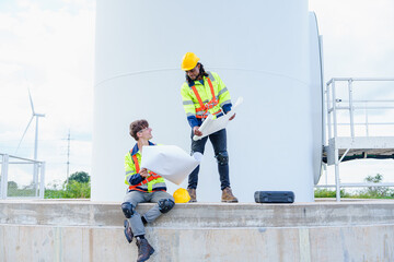 Technician engineer worker builders looking for wind turbine blueprint drawings for wind turbine construction at windmill field farm. Alternative renewable energy for clean energy concept.