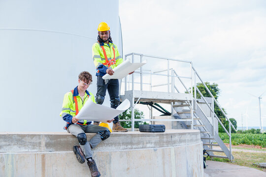 Technician engineer worker builders looking for wind turbine blueprint drawings for wind turbine construction at windmill field farm. Alternative renewable energy for clean energy concept.