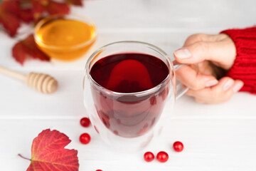 Woman's hand holds a mug with viburnum tea. Healthy vitamin drink. Close-up. Selective focus.