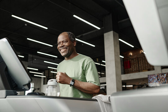 Medium low angle shot of happy senior african american runner training on treadmill at gym
