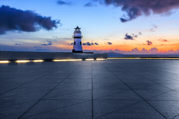 Empty square floor and lighthouse scenery at sunrise by the sea