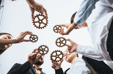 Below view office worker holding cog wheel as unity and teamwork in corporate workplace concept....