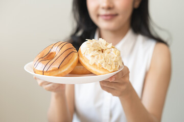 Close up donut plate with happy smile asian young woman, girl temptation food, enjoy eating sugar glazed doughnut and delicious dessert sweet, snack tasty. Eat fast food, junk food meal getting fat. - Powered by Adobe