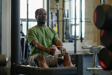Medium full shot of elderly african american sportsman doing abs exercise at gym sitting on bench