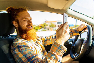 handsome redhaired ginger man with long beard going on trip during summer vacation on new car
