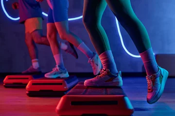 Photo sur Plexiglas Fitness Unknown gym goer stepping onto step platform with one leg with sportspeople exercising on background