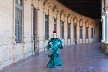 Fototapeta na wymiar Young and beautiful woman with typical green dress with ruffles and dancing flamenco in plaza de espana in seville, andalusia, walks with art and passion. 16 november, international flamenco day.