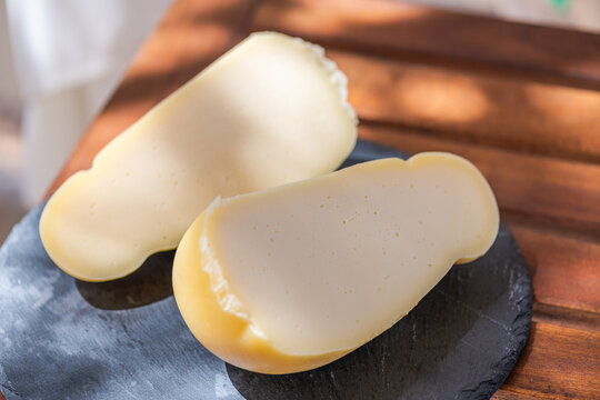 Caciocavallo cutting on a cutting board, is a matured pasta filata cheese typical of southern Italy. Made from cow's milk with the addition of rennet only, milk enzymes and salt, close up