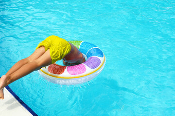 Child dives into pool with float; summer fun unleashed. Captures the joy of carefree childhood summers and active play.