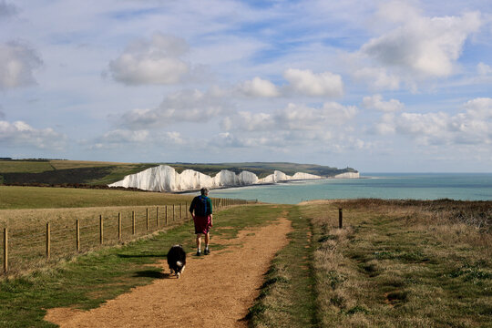 Walk in Cuckmere Haven near Seaford, East Sussex, England. South Downs National park. View of blue sea, cliffs, beach, green fields. 