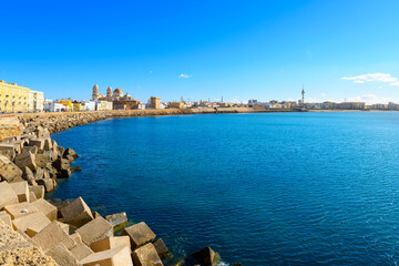 View from the rocky coastline and breakwater along Campo del Sur of the cityscape, Mediterranean Sea and historic Cadiz Cathedral, or Catedral de la Santa Cruz de Cádiz, in Cadiz Spain.  © Kirk Fisher