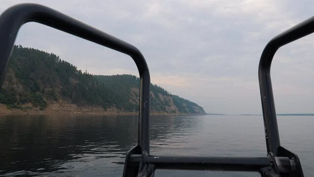 A boat sailing on the beautiful lake water with the mountainous landscape in background. Boat sailing on the clear lake in the natural scenery. Boat sailing on the clear lake water. Clouds