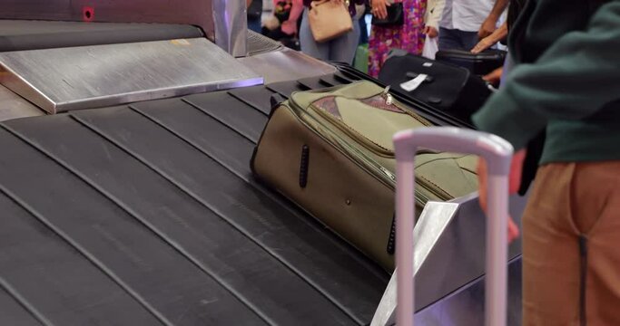 Various suitcases emerge and slide down on baggage carousel in airport arrival hall. Automated system pauses new bags if conveyor is full, then lowers them into available space