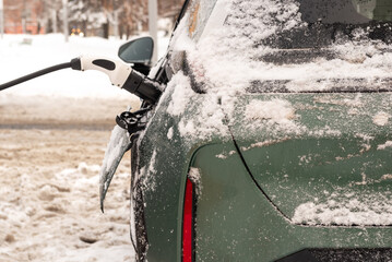 An electric car is charged from a charging station in winter. Eco transport. Energy