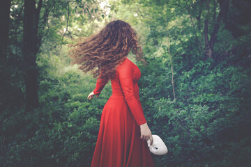 surreal woman dressed in red with mask in hand running free in the woods, abstract concept