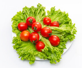 Green fresh lettuce leaves with juicy cherry tomatoes in a white bowl. Isolated on white background.