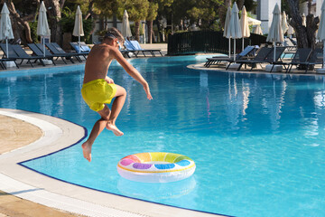 Modern day carpe diem: Youthful exuberance captured in a leap into cool pool waters amidst stylish...