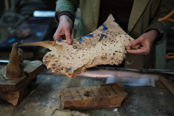 The detailed surface of the wood is inspected closely, showcasing the value placed on unique wood grains in the art of custom woodworking.