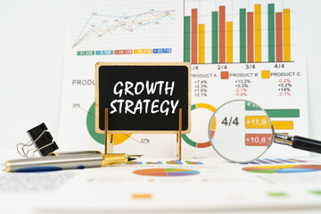 Against the background of business graphs, a board with the inscription - Growth Strategy - obrazy, fototapety, plakaty
