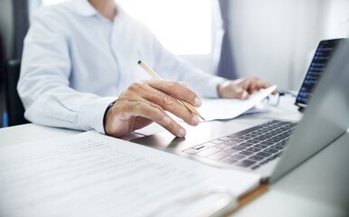 Close-up shot, businessman or lawyer holding pencil working with laptop and contact customer to give advice about business contracts, insurance and various important documents for start new business
