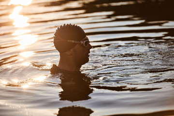 A triathlete finds serene rejuvenation in a lake, basking in the tranquility of the water after an...
