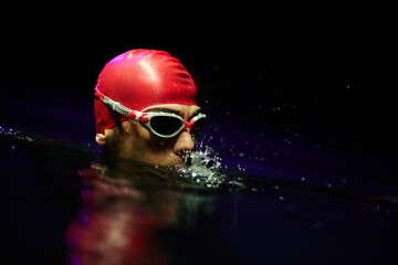 A determined professional triathlete undergoes rigorous night time training in cold waters,...