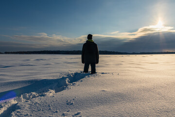 Young caucasian man standing in snow at sunrise. Czech winter landscape background