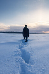 Young caucasian man standing in snow at sunrise. Czech winter landscape background