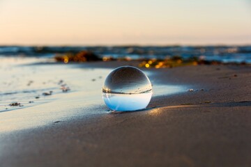 Fototapeta na wymiar Beach and sea reflected in a sphere lying in the sand in the waves
