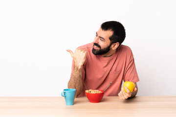 Caucasian man having breakfast in a table pointing to the side to present a product.