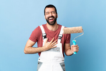 Adult painter man over isolated blue background smiling a lot