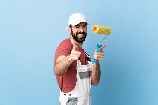 Adult painter man over isolated blue background pointing to the front and smiling