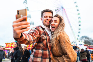 Couple having fun and taking a selfie at amusement park in London