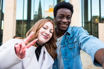 Multiracial couple taking a selfie together and smiling at camera